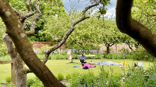 A sound gong bath taking place in the walled garden at Grantham House.